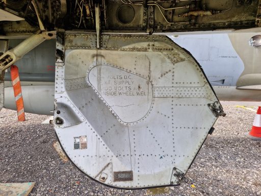 Detail of a metallic panel on an aircraft, featuring text and rivet patterns.