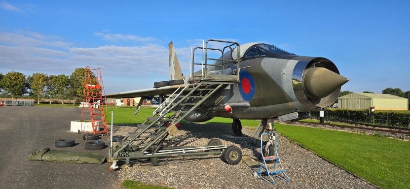A military jet displayed outdoors, with a ladder for access.