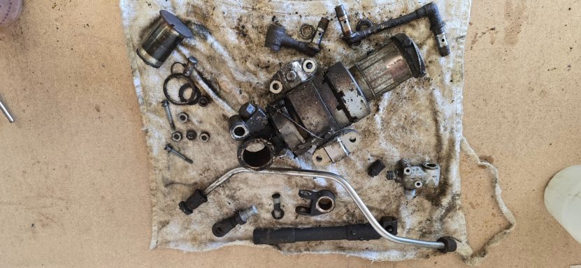 Disassembled mechanical parts and tools on a stained cloth surface.