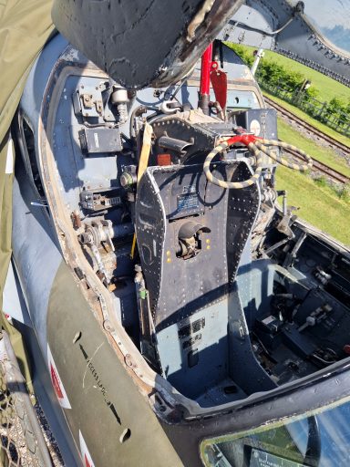Cockpit of a military aircraft with controls and seat visible from a high angle.