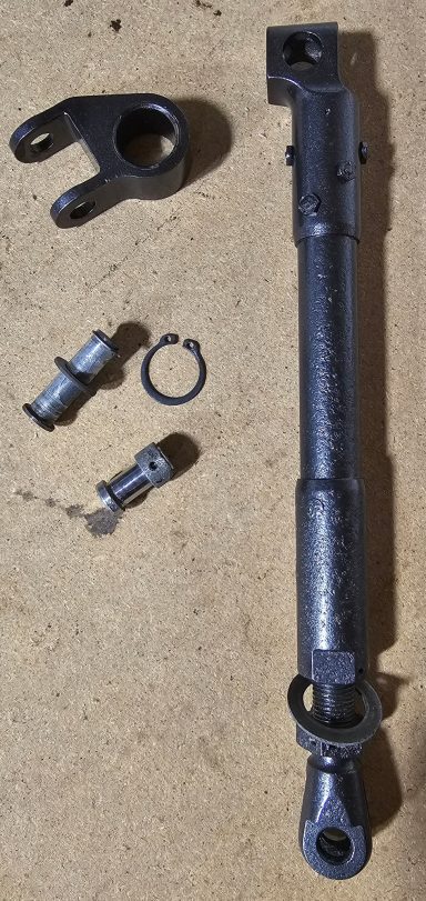 Black mechanical component with joints and fittings on a wooden surface.