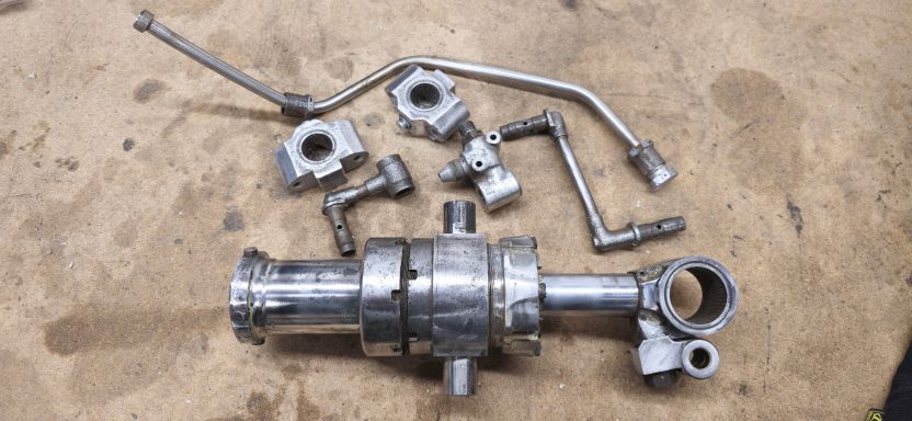 Metal components including pipes and connectors, arranged on a wooden surface.