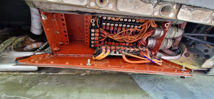 Close-up of a circuit board with orange wiring and metal casing.