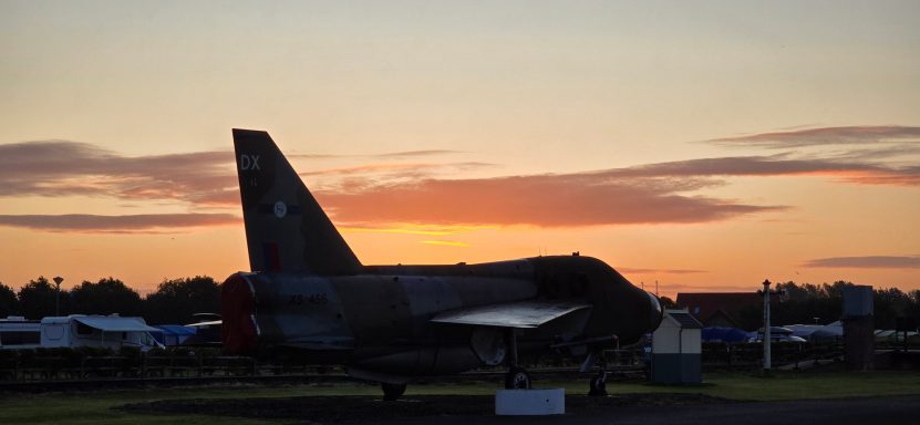 Silhouette of a military aircraft against a sunset sky.